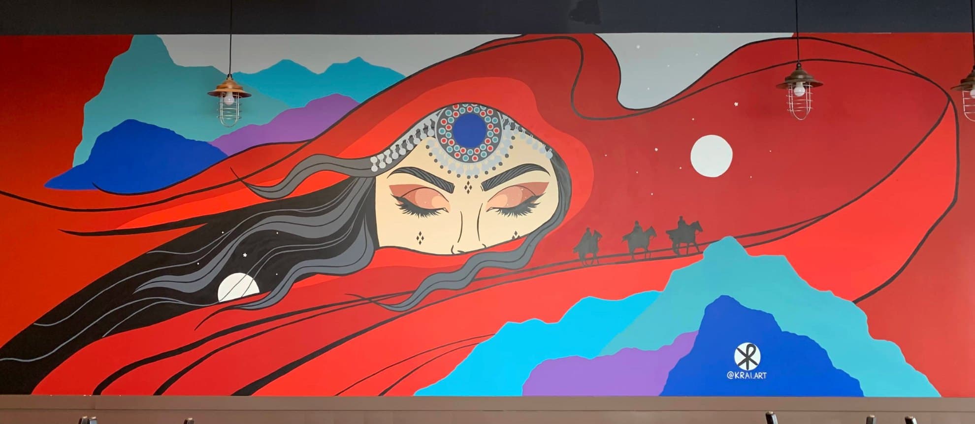 Across the Veil at Noor's Curry and Grill in Sunridge, Calgary: a woman with closed eyes wrapped in a sweeping red veil, camel riders on the horizon
