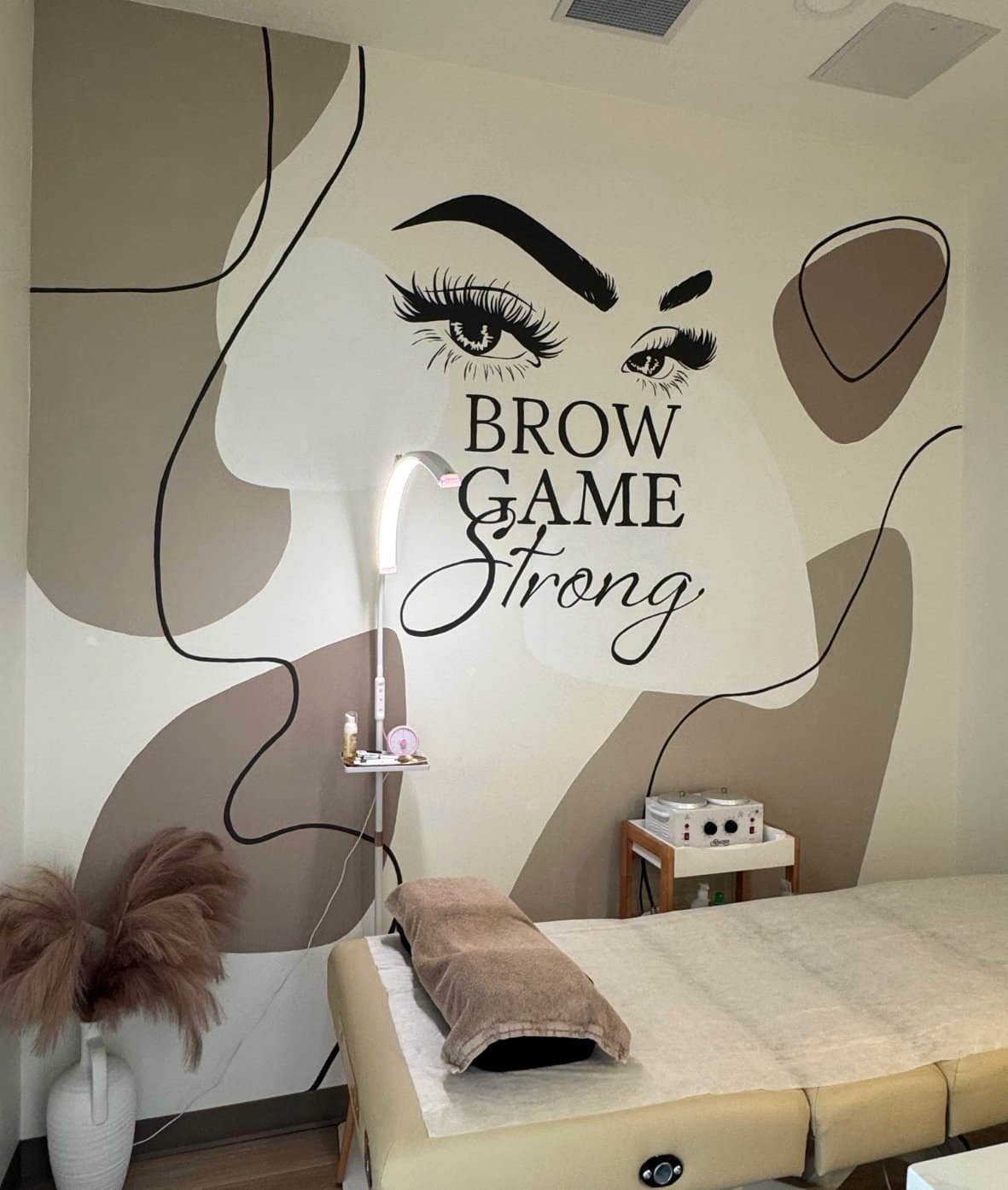 Brow Game Strong at Lavish Beauty Laser Med Spa in Cornerstone, Calgary: a line-drawn face with bold brows and lashes above a treatment bed