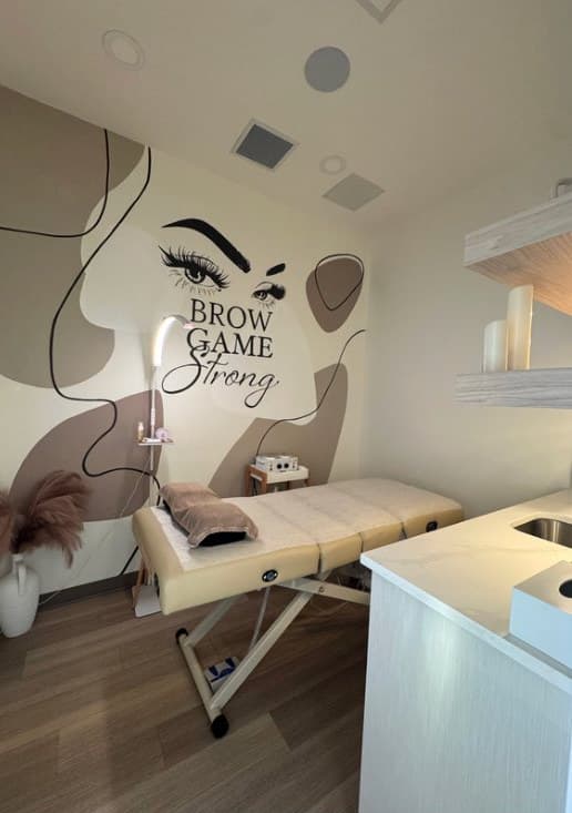 The treatment room at Lavish Beauty, with Brow Game Strong on the wall behind the bed
