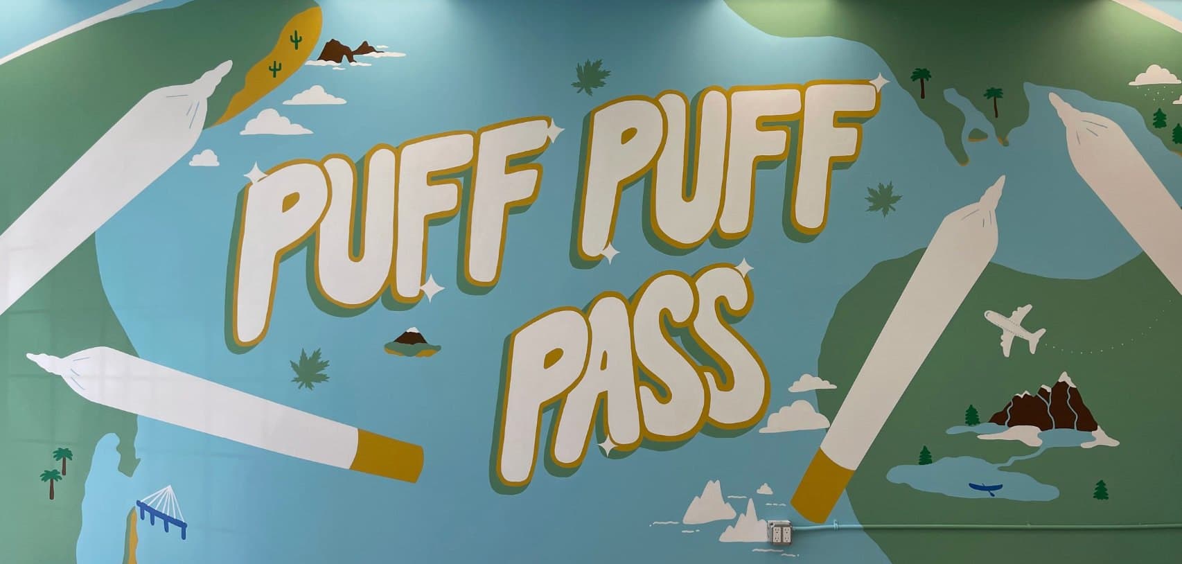 Puff Puff Pass at Bud Mart Cannabis in Copperpond, Calgary: gold lettering between two giant joints over a pale green landscape