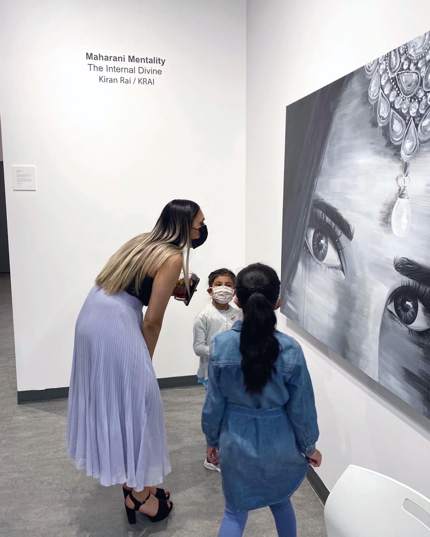 Kiran Rai-Bhullar talking with two young visitors beside the Maharani Mentality title wall