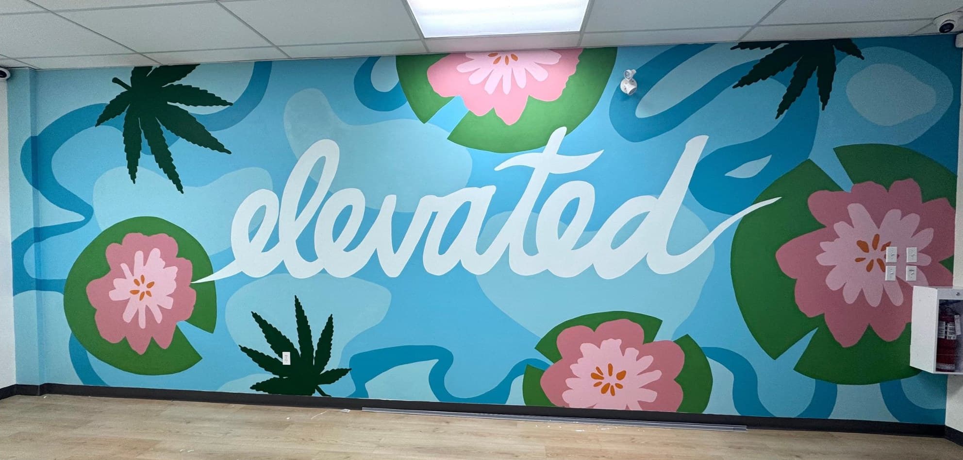Elevated at Bud Mart Cannabis in Airdrie: the word elevated in white script over pink lotus blossoms and cannabis leaves on blue
