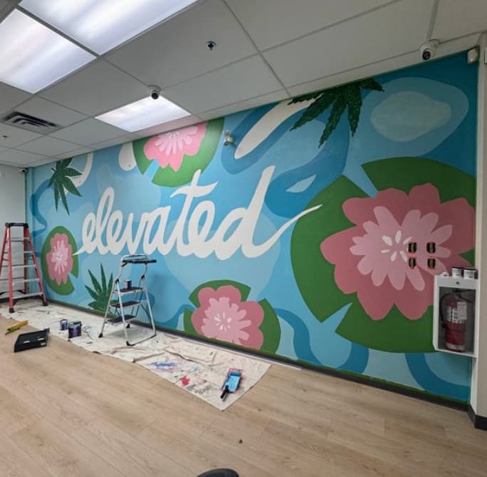 Elevated in progress: the lettering and lotus flowers on the wall, ladders and drop cloths on the floor