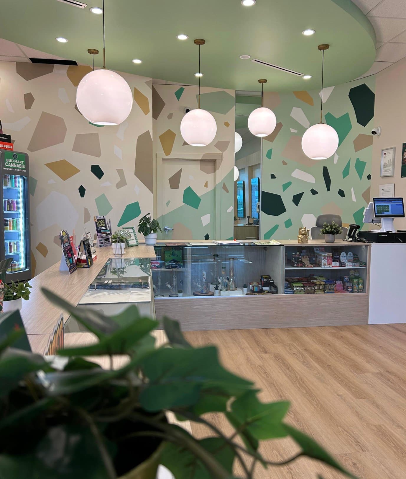 Mosaic Earth at Bud Mart Cannabis in Skyview, Calgary: terrazzo shapes in greens and sand tones across the walls above the counter