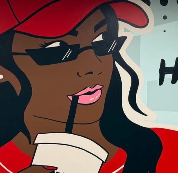 Close-up of Pekko: a woman in a red cap and dark glasses sipping a drink through a straw