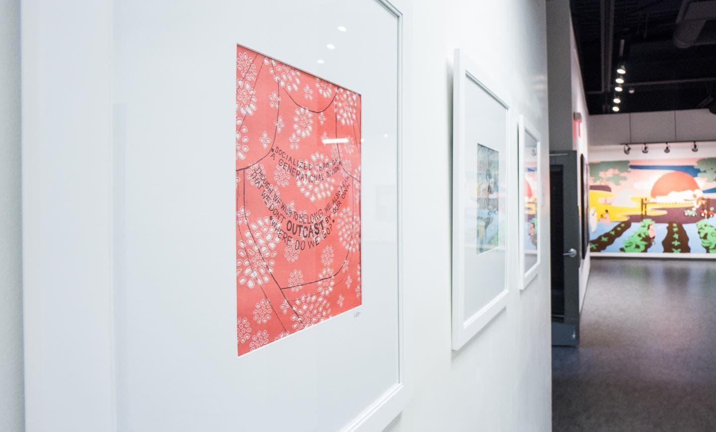 Close view of the coral print, lines of poetry drawn in the shape of a necklace, with the Love for Humanity mural through the doorway