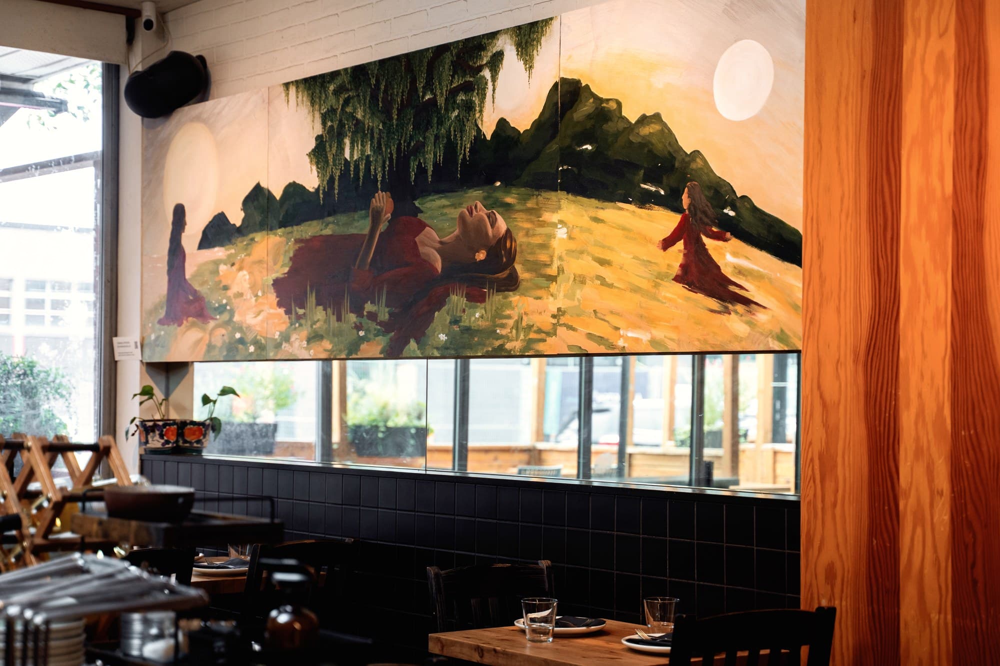 A Woman’s World seen from the dining room at UNA Pizza + Wine, beside the timber column